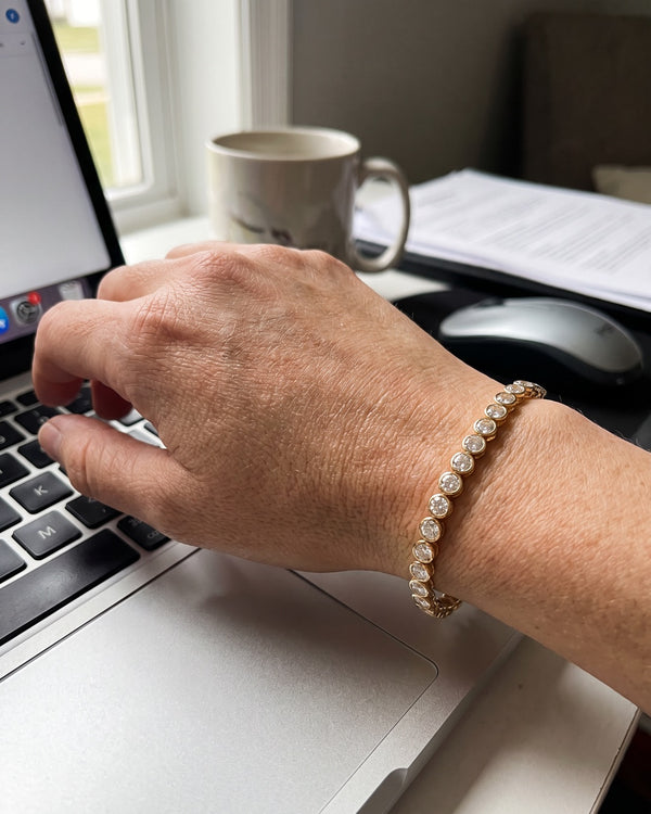 Tennis bracelet on a wrist at a laptop
